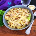 A plate with Pasta Bake, containing tender roasted pieces of chicken, crispy bacon and broccoli in a creamy parmesan sauce, topped with melted cheese.